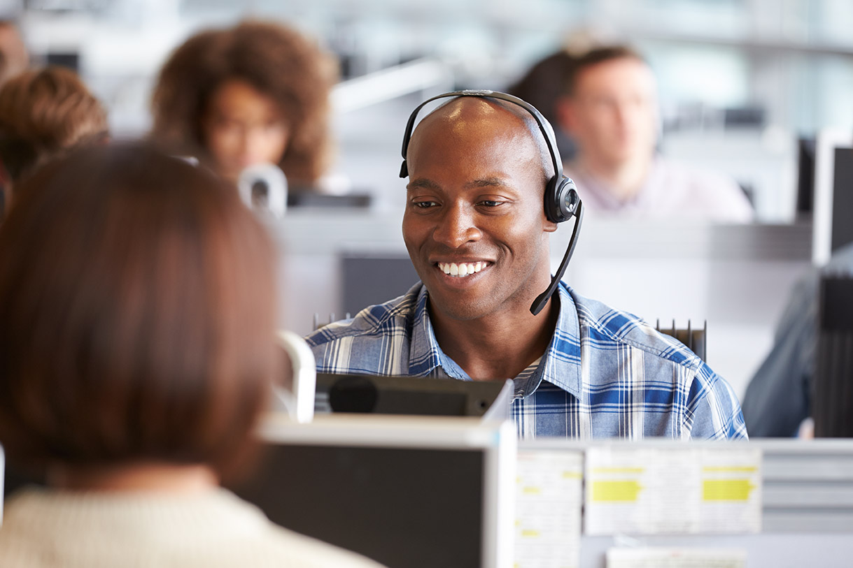 man smiling while talking to someone on a headset