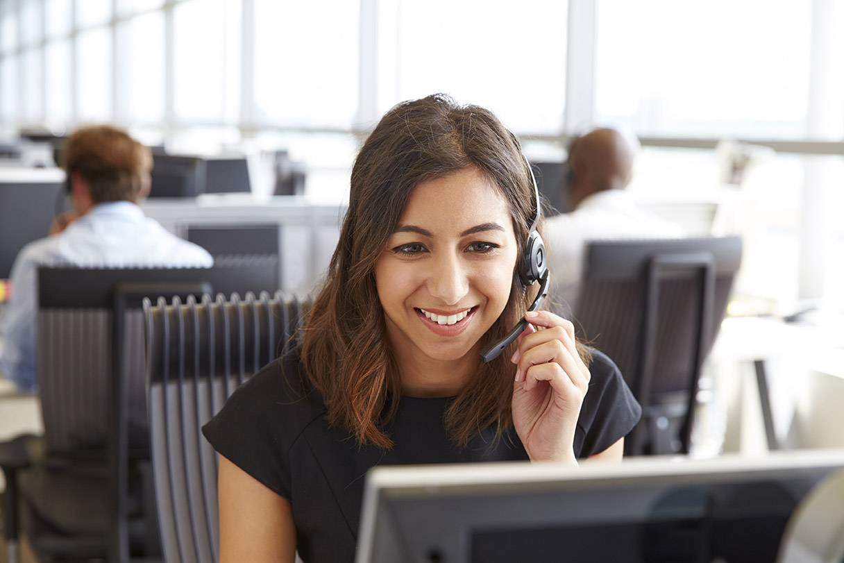 woman speaking on a headset in front of computer